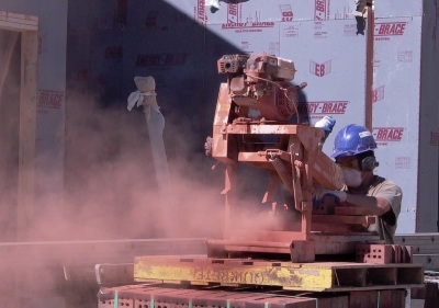 construction worker sawing dry brick releasing dust containing silica